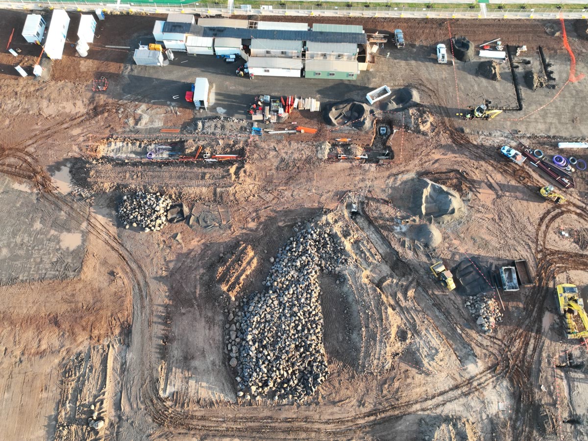 Tarneit North Primary School (interim name) - construction photo of site progress in February 2023 - aerial shot of site showing flattened earth, building stone, construction vehicles and portables