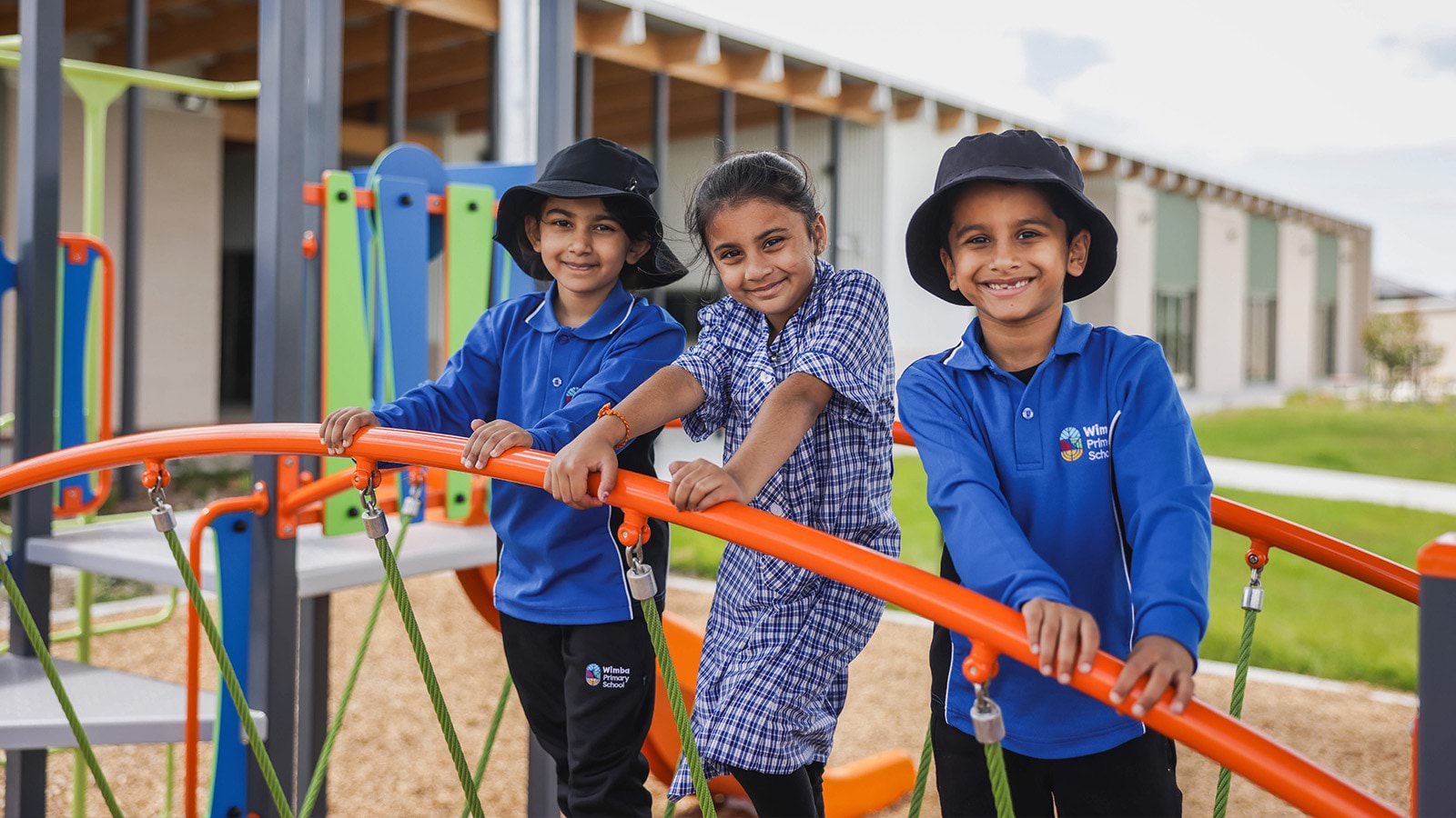 Young students wearing school uniforms stand on playground equipment