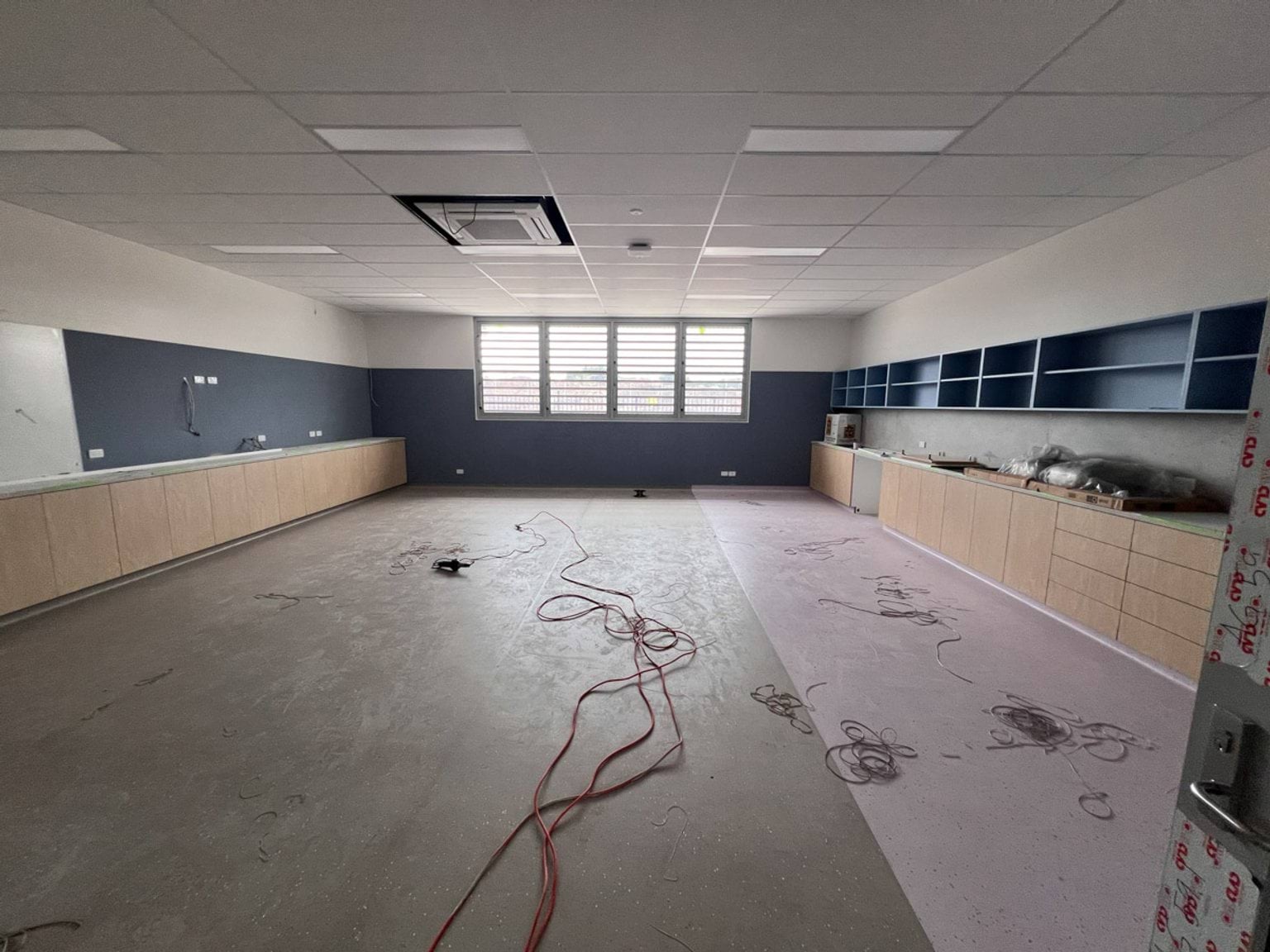 New classroom constructed with a blue, white, timber, and pink colour palette. Electrical cabling strewn across the floor.