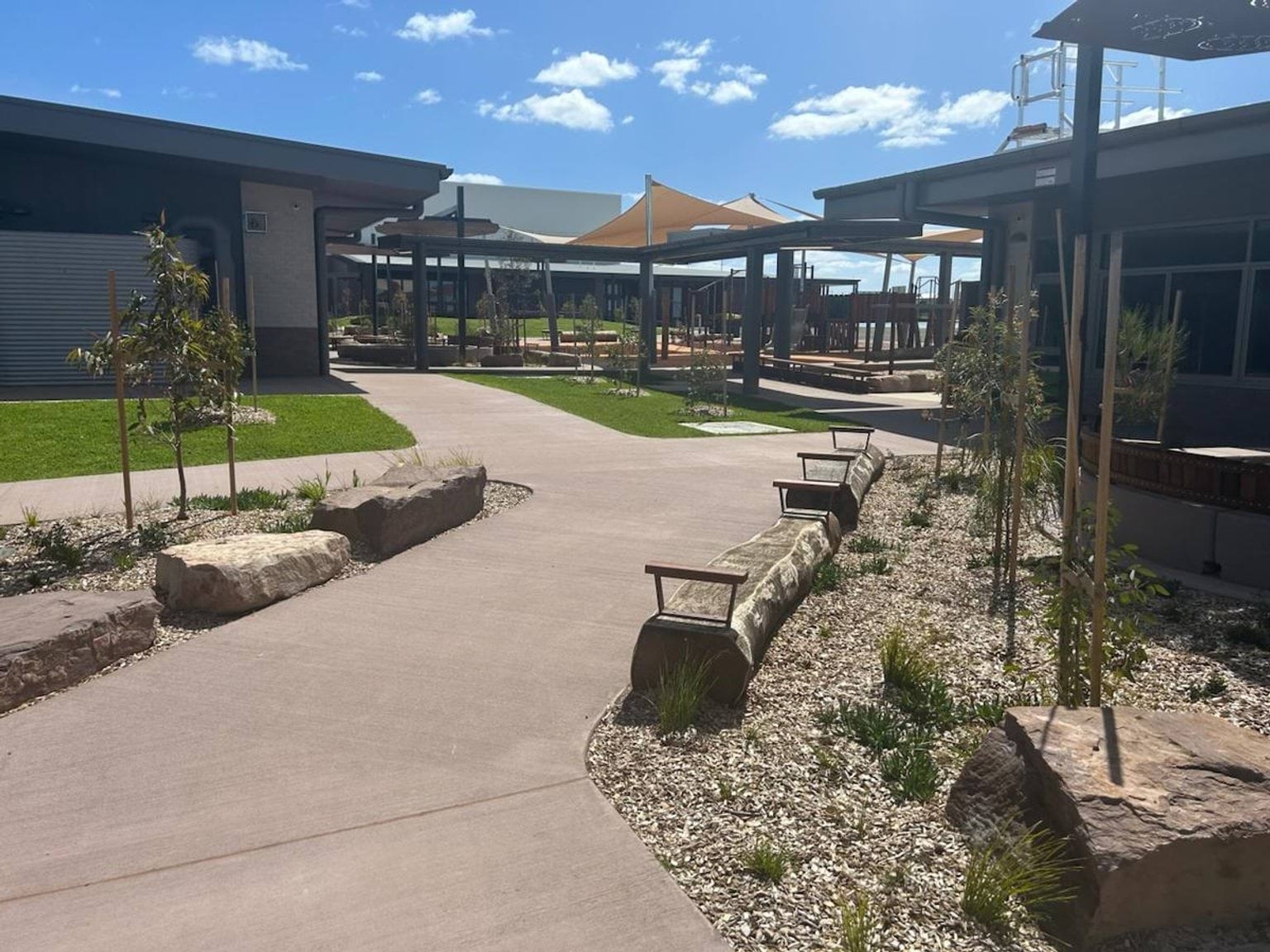 Landscaped courtyard between Mindalk Primary School buildings that features a path an seats made from logs.