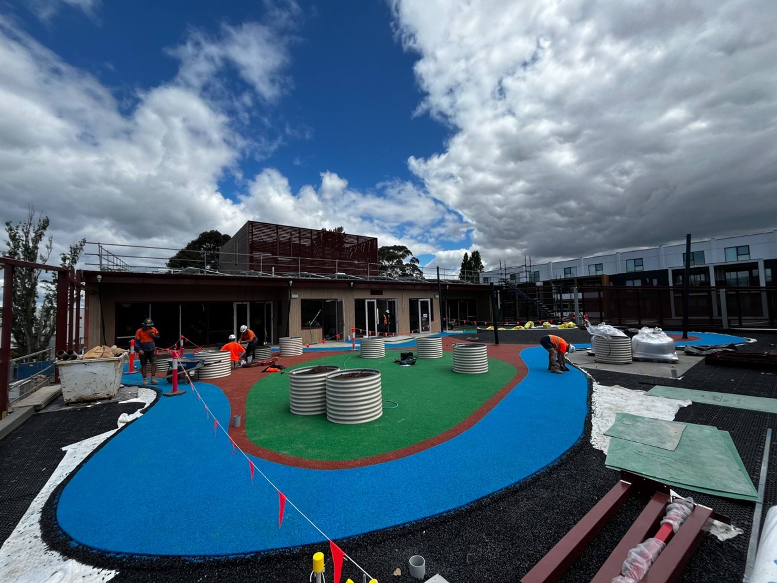Colourful playground with barrel raised garden beds.