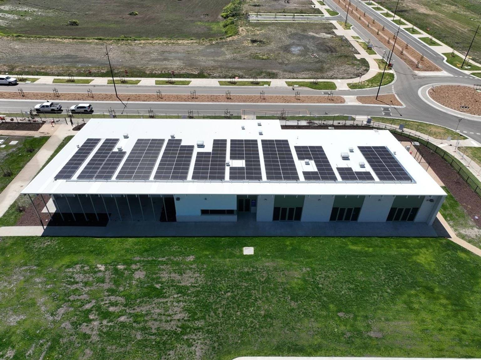 A photo of a new school building at Muyan Primary School taken from a high angle. There are solar panels on the roof, and grass is growing in front of it.