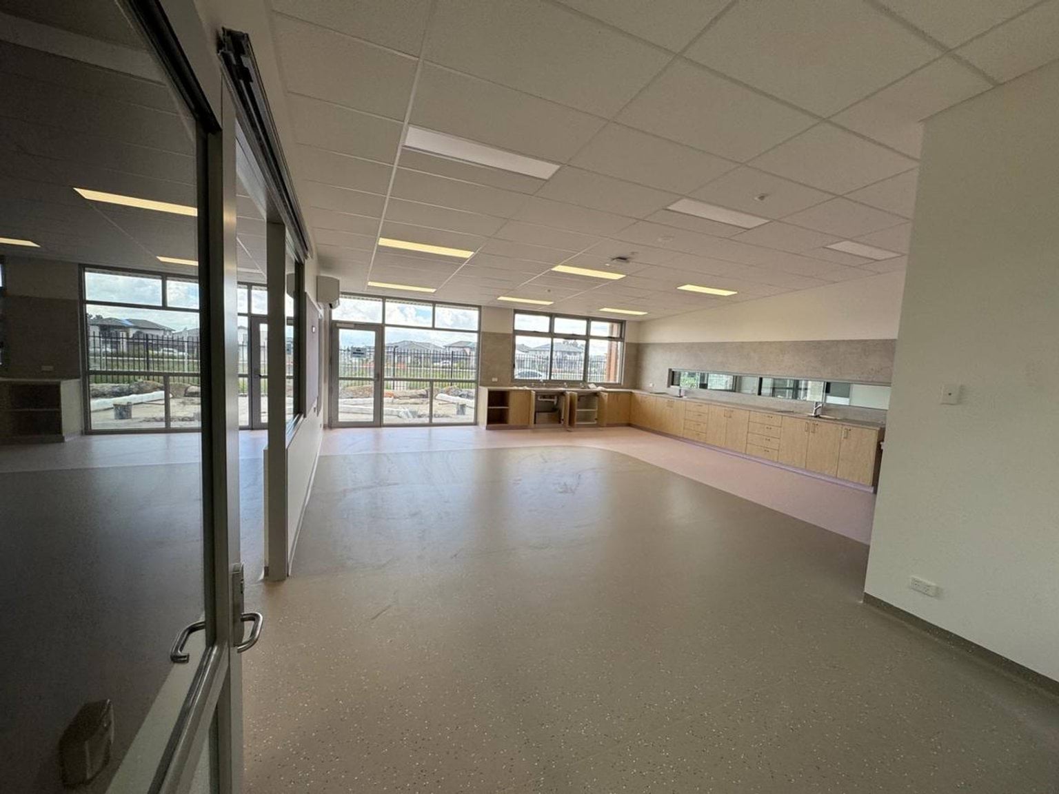 School room under construction. There are shelves and mirrors against the wall, and large windows at the rear.