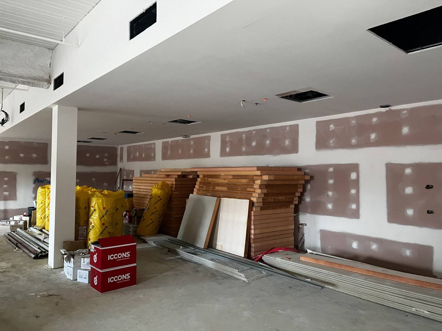 Stacks of wood placed against a wall that is under construction