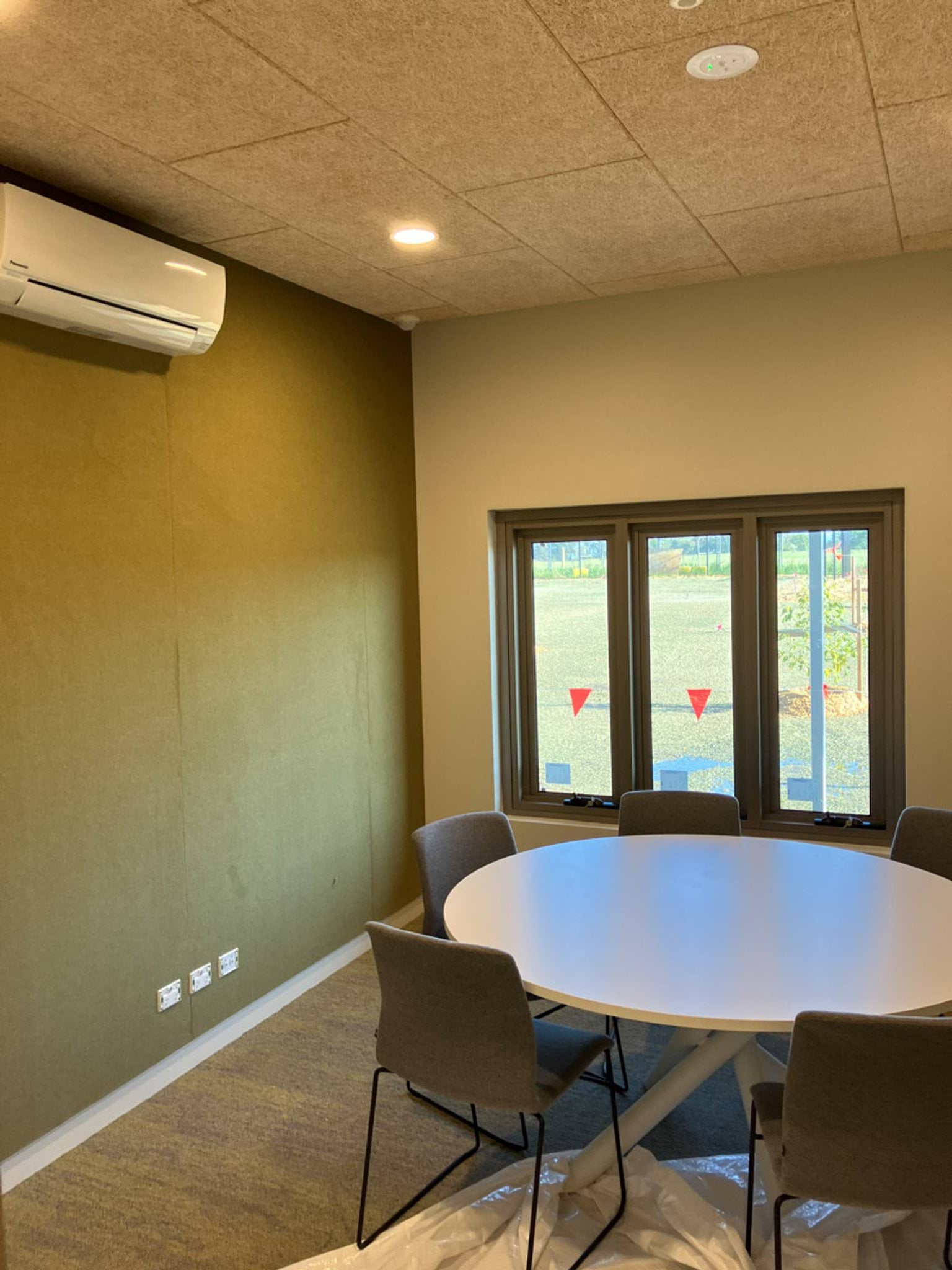 Photo of round table surrounded by chairs inside room with windows and air conditioner